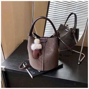 Detail of vintage brown suede bucket bag with round handle and plush glove charm