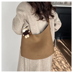 Sac hobo marron en similicuir avec pendentif ours, porté par un mannequin en intérieur