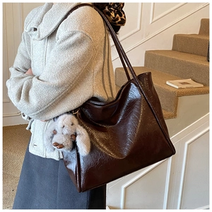 Detail of dark brown vintage tote bag with glossy texture and plush bunny charm