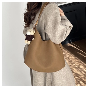 Sac hobo en cuir marron avec pendentif ours en peluche porté en bandoulière détail
