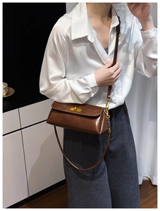 Detail of a dark brown leather shoulder bag featuring a vintage gold metal twist lock
