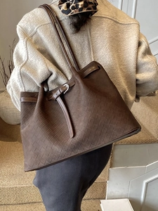 Brown woven leather tote bag for women with dual shoulder straps shown in lifestyle use