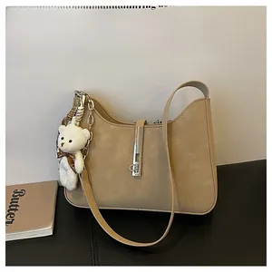 Detail view of khaki hobo bag featuring silver metal buckle and white plush bear charm
