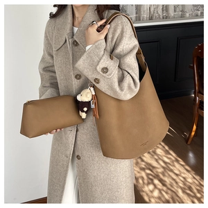 Détail du sac seau en cuir marron avec charme d'ours sur un manteau en laine