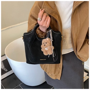 Close-up of black matte bucket bag featuring a cute brown plush bear charm detail