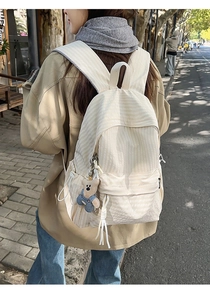 Close-up of cream striped backpack with a cute blue teddy bear pendant detail