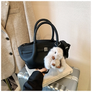 Detail of black pebbled leather bucket bag with a cute white plush bunny charm