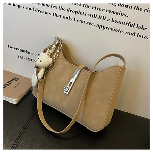 Detail of hobo underarm bag in khaki suede featuring silver buckle and plush bear charm