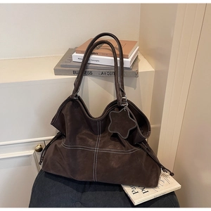 Detailed view of dark brown tote bag showing white contrast stitching and star charm