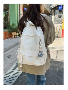 Detail of checkered canvas backpack with side drawstring pockets and cute bear charm