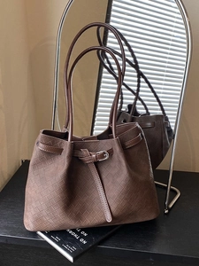 Dark brown woven leather tote bag with buckle detail shown with creative mirror reflection