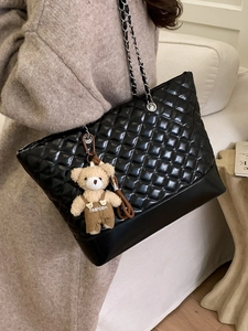 Quilted black tote bag with silver chain straps and a cute plush bear charm accessory