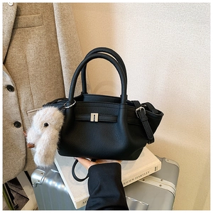 Close-up of black lychee leather bucket bag featuring a plush bunny and silver buckle