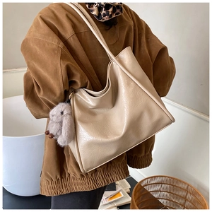 Detail of beige large capacity tote bag with glossy crinkled leather and bunny charm