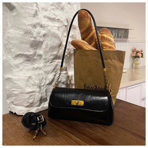 Detail of black glossy shoulder bag with gold twist lock and extra wide adjustable strap