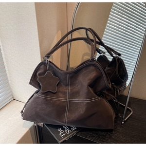 Detail of dark brown tote bag with white contrast stitching and star leather charm