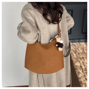 Gros plan du sac hobo en cuir caramel avec breloque ours et finition texturée