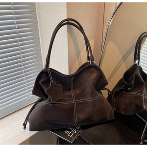 Detail of dark brown leather tote bag with white contrast stitching and star charm