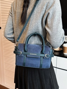 Grand sac à main bleu sarcelle en daim avec boucles métalliques porté par un modèle