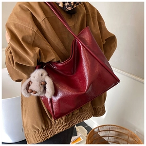 Macro detail of large burgundy tote bag in glossy soft leather with plush rabbit charm