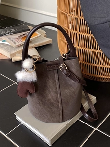 Vintage brown faux suede bucket bag with plush charm and adjustable shoulder strap