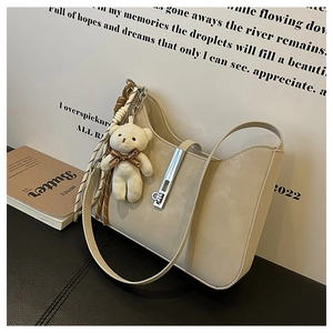 Close-up of beige moon bag with silver buckle and cute bear charm with Love ribbon