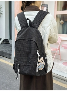 Detail of checkered backpack with cute bear pendant and spacious front zipper pockets