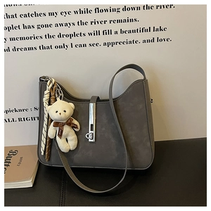 Detail of grey suede hobo bag with silver buckle and plush bear charm pendant