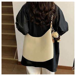 Sac demi-lune beige minimaliste avec pendentif ours porté par le mannequin