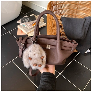 Close-up of dark brown lychee grain leather bucket bag with cute plush rabbit charm