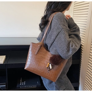 Detail of vintage brown crocodile texture tote bag featuring a plush charm and metal buckle