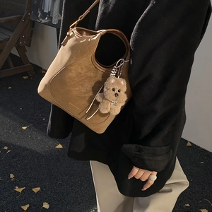 Brown retro bucket bag with teddy bear charm shown in an autumn street setting