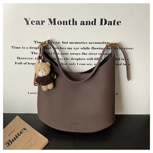 Détail du sac en cuir litchi marron avec boucle dorée et breloque ours mignonne