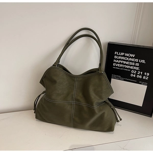 Detail view of olive green leather tote with white cross stitching and side drawstrings