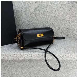 Close-up of a black textured leather crossbody bag with a gold rectangular twist lock