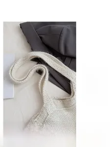 Macro detail of the wide knitted shoulder strap on a thick white woolen tote bag