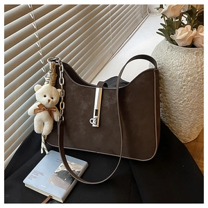 Detail of dark brown suede shoulder bag with silver buckle and plush bear charm