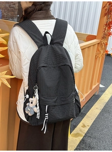 Detail of black plaid backpack with cute plush bear pendant and double zipper pockets