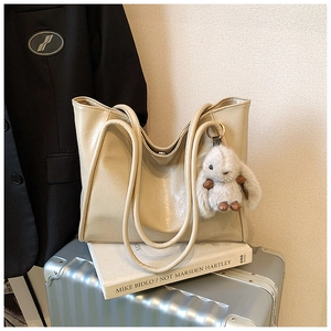 Detail of cream large tote bag with soft leather texture and plush rabbit charm