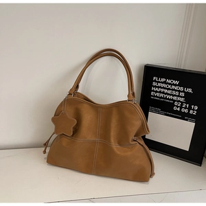 Detail of brown faux leather tote bag featuring contrast stitching and star charm