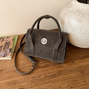 Close-up of retro charcoal grey leather crossbody bag with circular metal twist lock detail