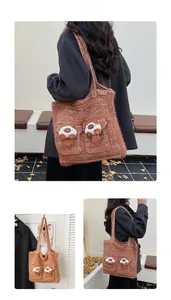 Detail view of brown knitted tote bag with cute 3D plush cat charms and front dual pockets