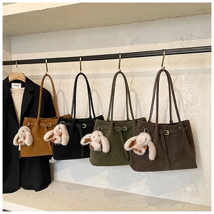 Detail view of four colorful suede tote bags with cute rabbit charms on a stone background