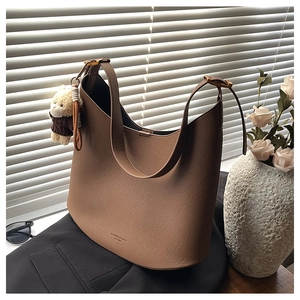 Détail du sac hobo en cuir marron avec breloque ours et boucle dorée réglable