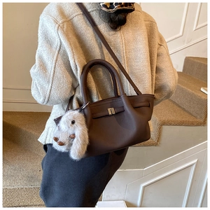 Detail of dark brown pebble leather bucket bag with silver buckle and plush rabbit charm