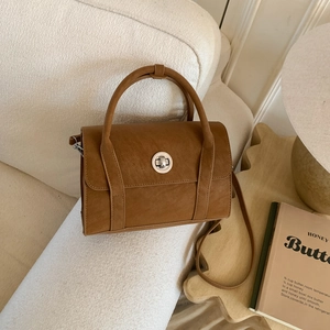 Brown vintage faux leather crossbody bag with silver clasp on a warm lifestyle background