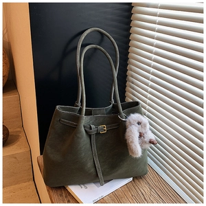 Detail of dark green suede tote bag featuring long straps and a plush bunny charm