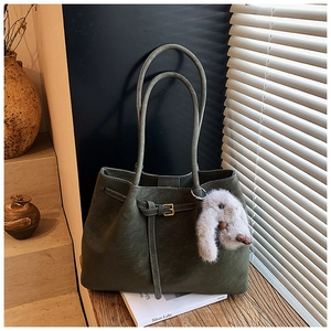 Detail of dark green leather tote bag with gold buckle and cute white bunny charm
