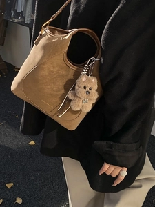 Brown retro suede bucket bag with bear pendant and shoulder strap in autumn street scene