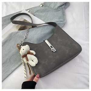 Flat lay of dark gray matte shoulder bag with silver buckle and cute teddy bear charm